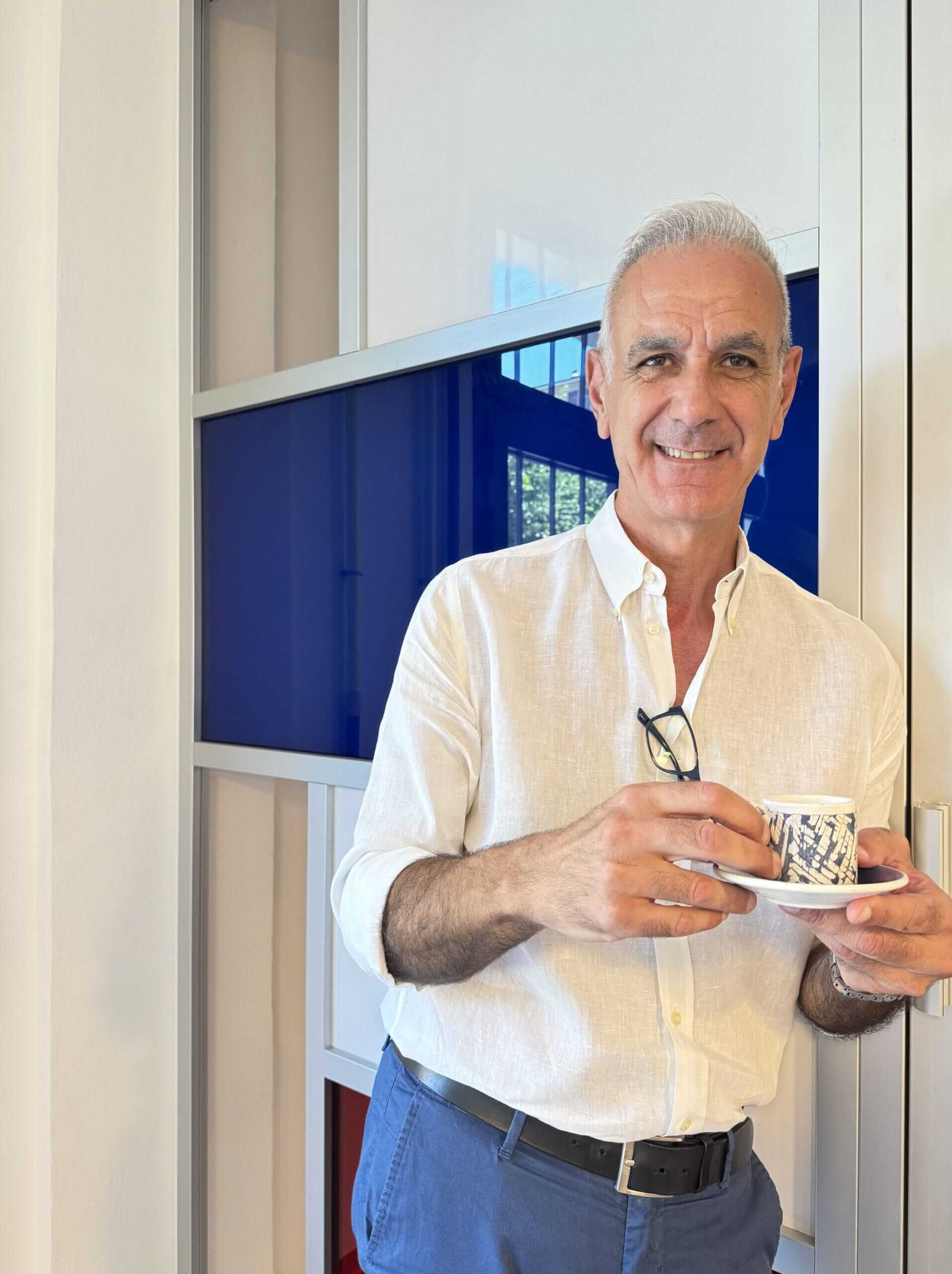 Aurelio Pellicciotti, agente immobiliare a Bologna, con tazzina di caffè simbolo di accoglienza e consulenza personalizzata.